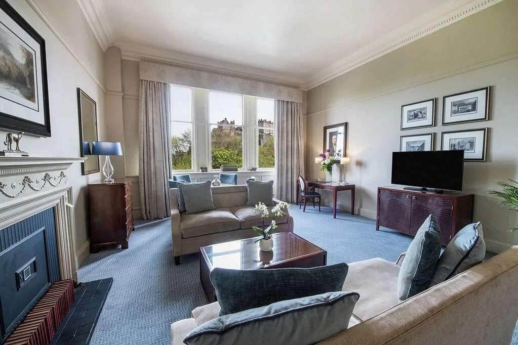 Luxuriöser Wohnbereich der Suite mit Sofas und Ausblick auf Edinburgh Castle