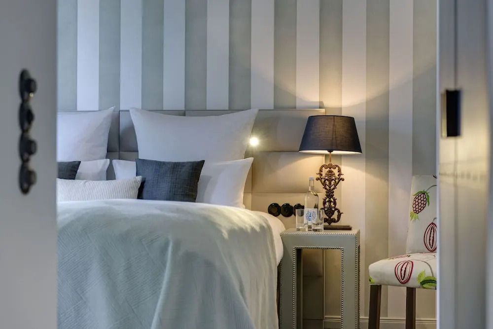 Elegantes Bettdesign in der Junior-Suite mit gestreiftem Hintergrund und Lampe