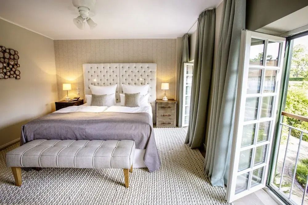 Helles Schlafzimmer in der Junior-Suite mit großen Fenstern und stilvollem Kopfteil