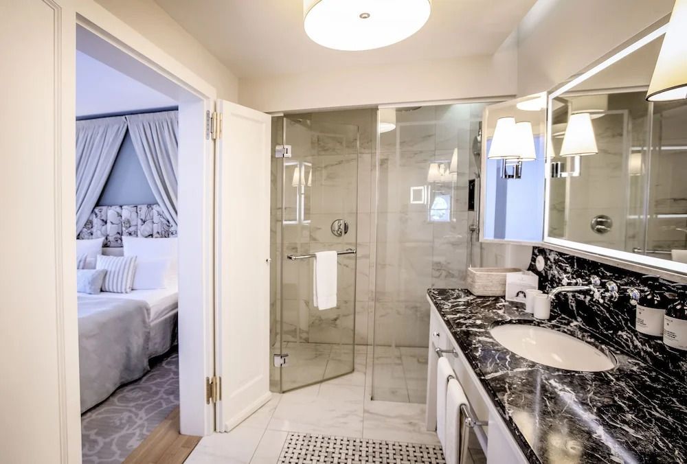 Luxuriöses Badezimmer mit Marmorakzenten und Glasdusche neben Schlafbereich