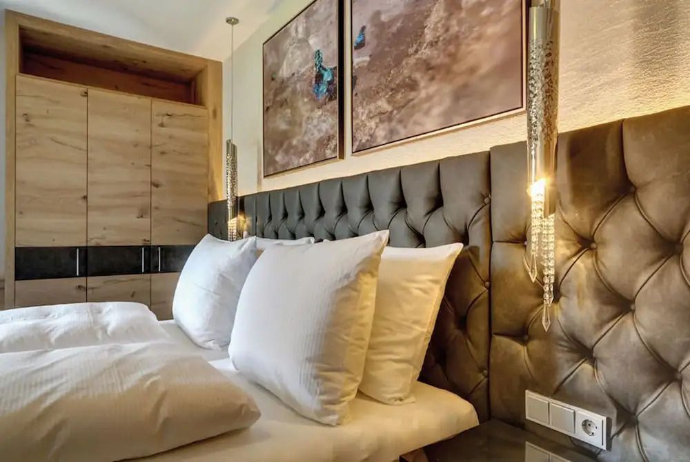 Elegantes Schlafzimmer mit Polsterbett und Holzelementen in der Deluxe Suite