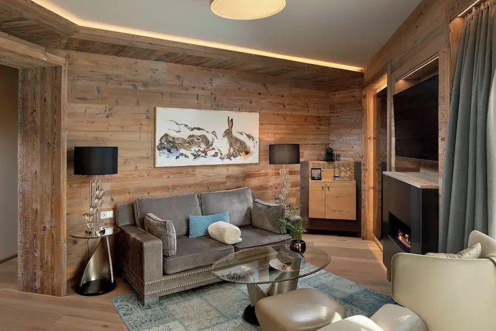 Gemütliches Wohnzimmer in der Deluxe Suite mit Kamin und Holzverkleidung