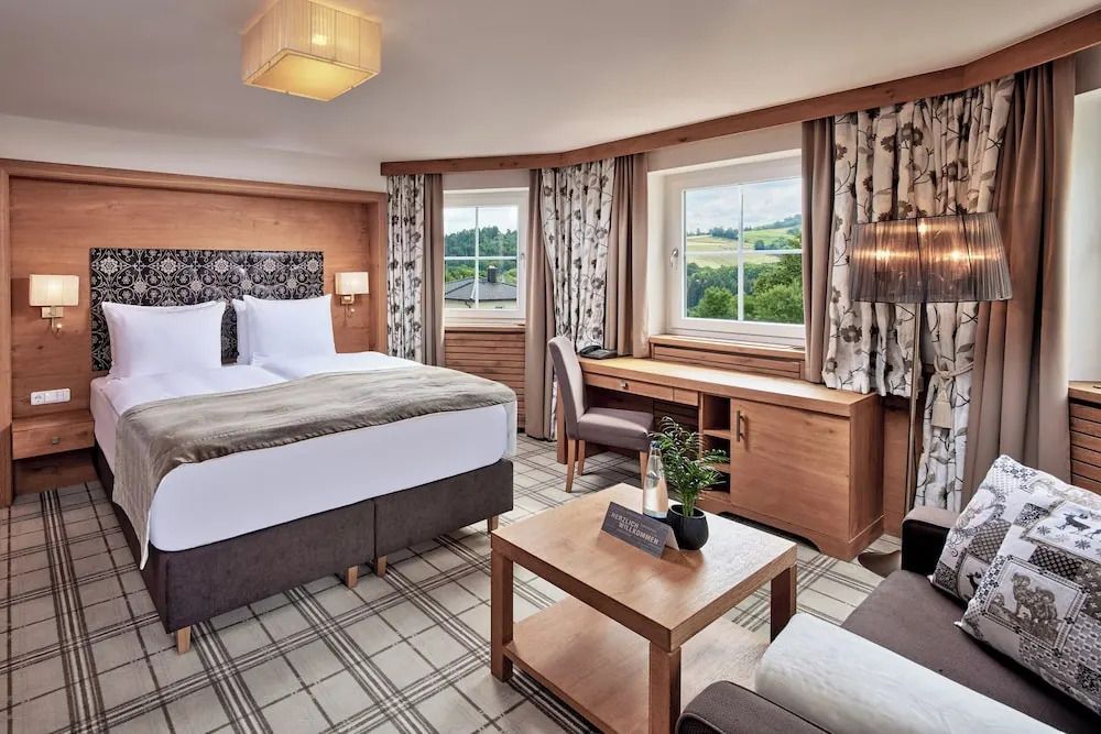 Komfort Doppelzimmer mit luxuriösem Doppelbett und Schreibtisch mit Blick in die Natur