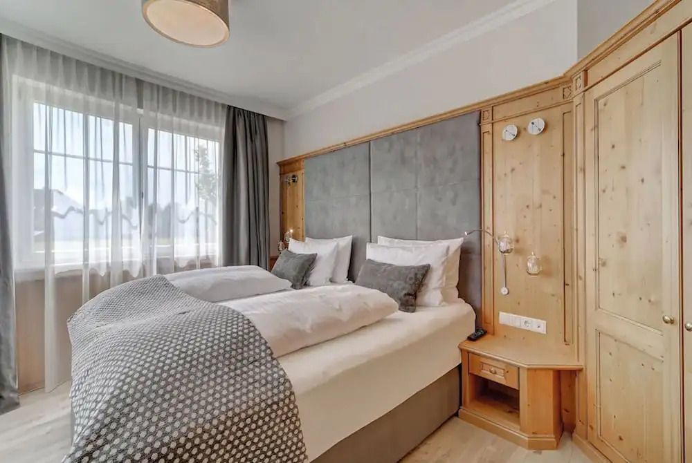 Gemütliches Schlafzimmer in einer luxuriösen Suite mit Doppelbett und großen Fenstern