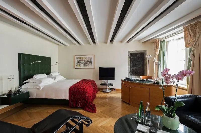 Geräumiges Zimmer mit Doppelbett, roter Decke, stilvollen Möbeln, TV.