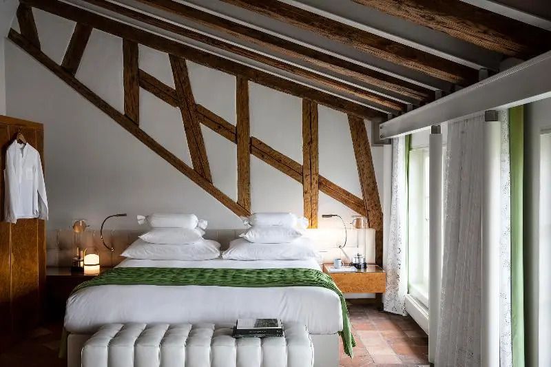 Zimmer mit Dachbalken, grüne Akzente, großes Fenster, modernes Design.
