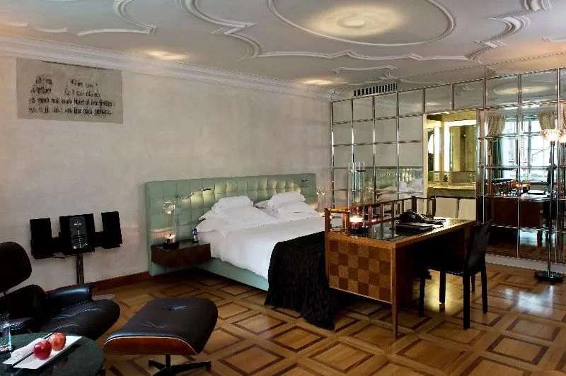 Luxuriöses Zimmer mit grünem Kopfteil, Spiegelwand, edle Möbel, Parkettboden.
