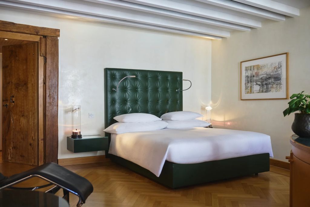 Modernes Doppelzimmer mit grünem Kopfteilelement und elegantem Holzboden