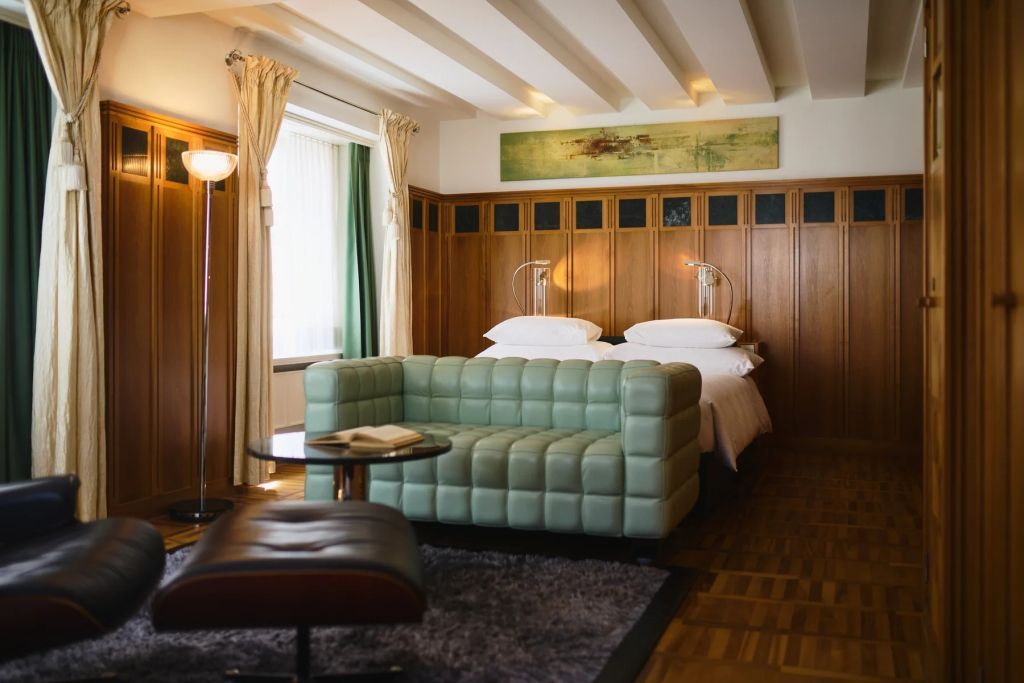 Luxuriöses Zimmer mit grünem Sofa, Holzwänden und großem Doppelbett