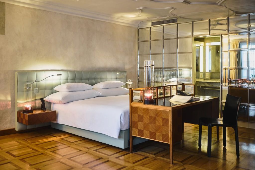 Zimmer mit Mosaikspiegel und edlem Holzschreibtisch neben einem großen Bett