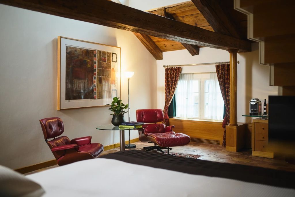 Elegante Sitzecke mit roten Sesseln und Kunstwerk in der Duplex Junior-Suite