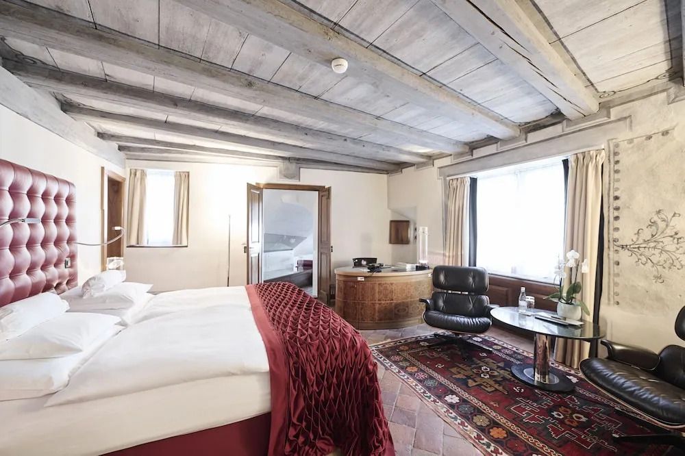 Geräumiges Zimmer mit gemütlichem Bett und stilvollem Ledersessel