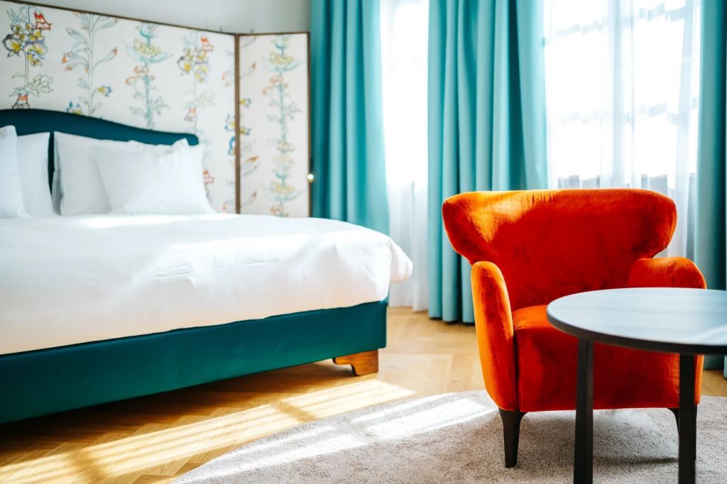 Modernes Schlafzimmer mit orangem Sessel und blauen Vorhängen