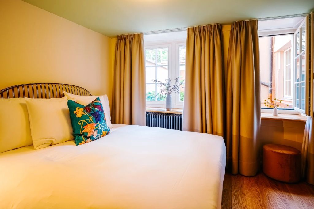 Elegantes Schlafzimmer mit großem Bett und farbigen Kissen im historischen Stil