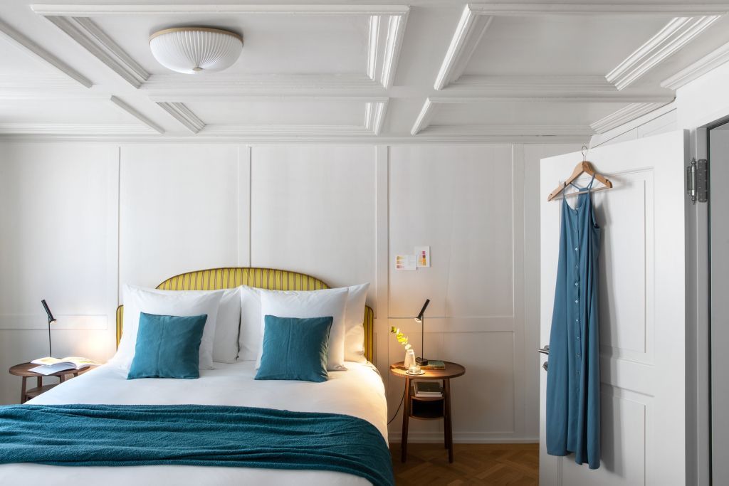 Luxuriöses Schlafzimmer mit weißen Wänden, blau-gelben Akzenten und eleganter Beleuchtung