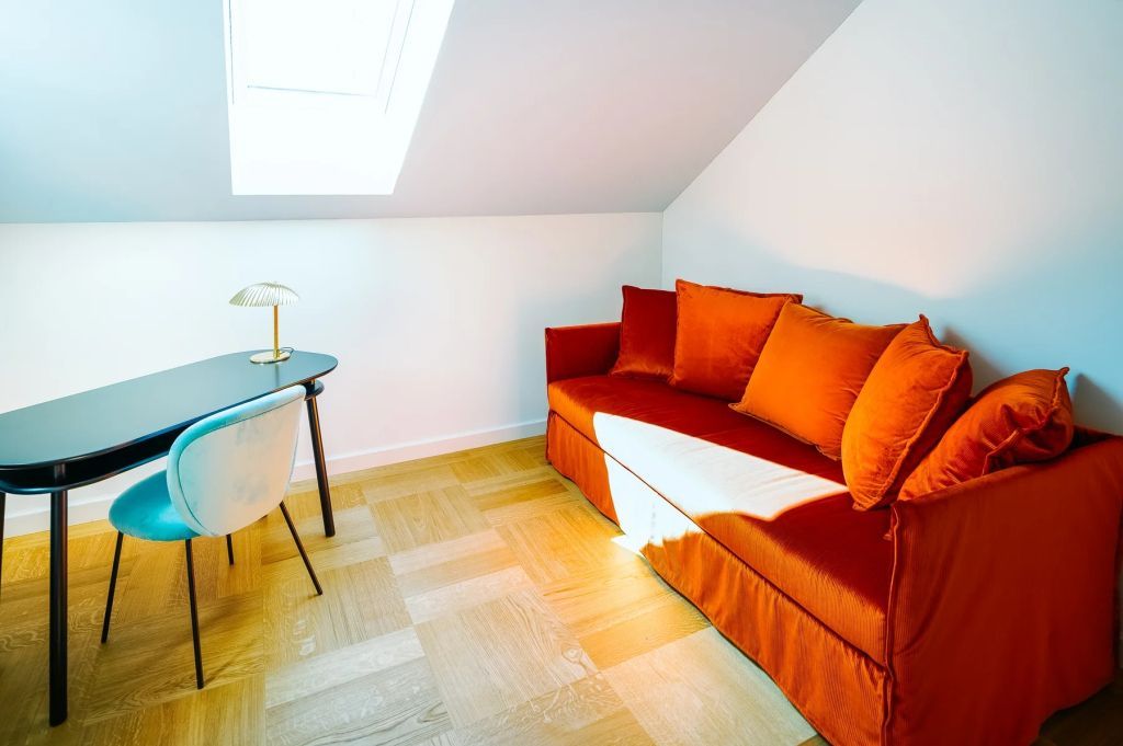 Kompakter Arbeitsbereich mit rotem Sofa und Dachfenster, elegante Einrichtung