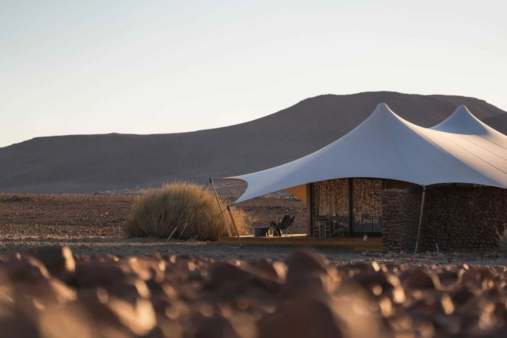 Luxuriöse Zeltsuite in der Wüstenlandschaft bei Sonnenuntergang mit malerischem Ausblick