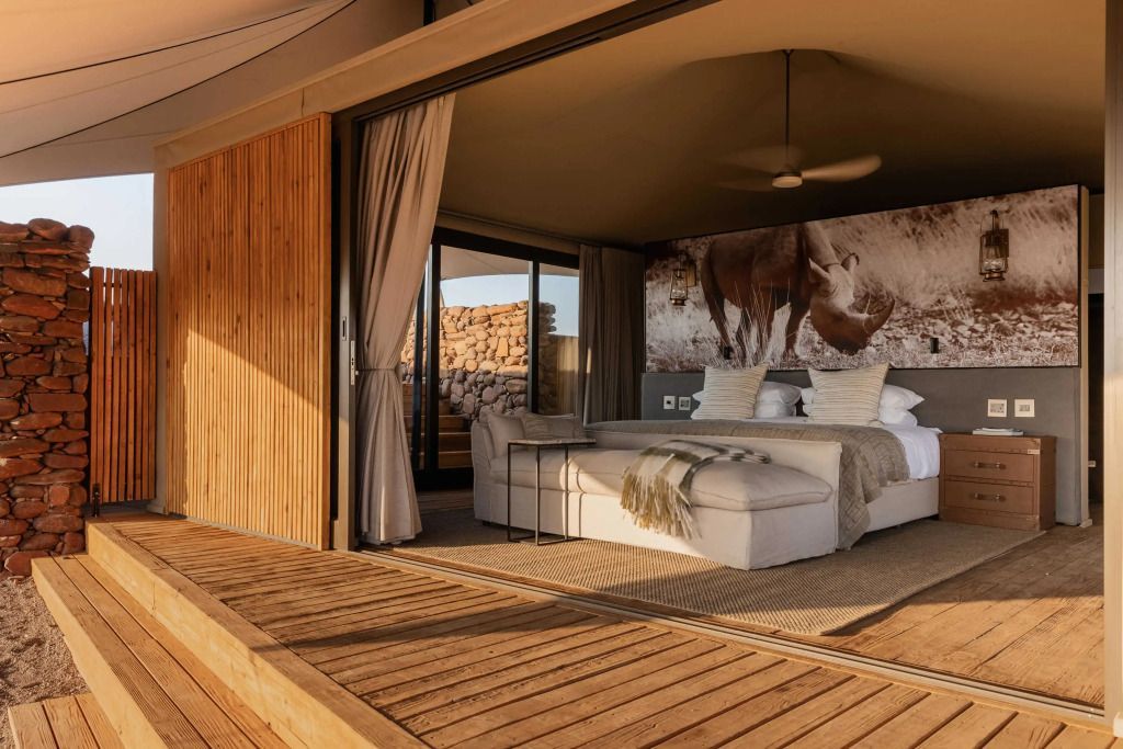 Elegantes Standardzimmer mit offenem Design und großem Bett im Wilderness Desert Rhino Camp