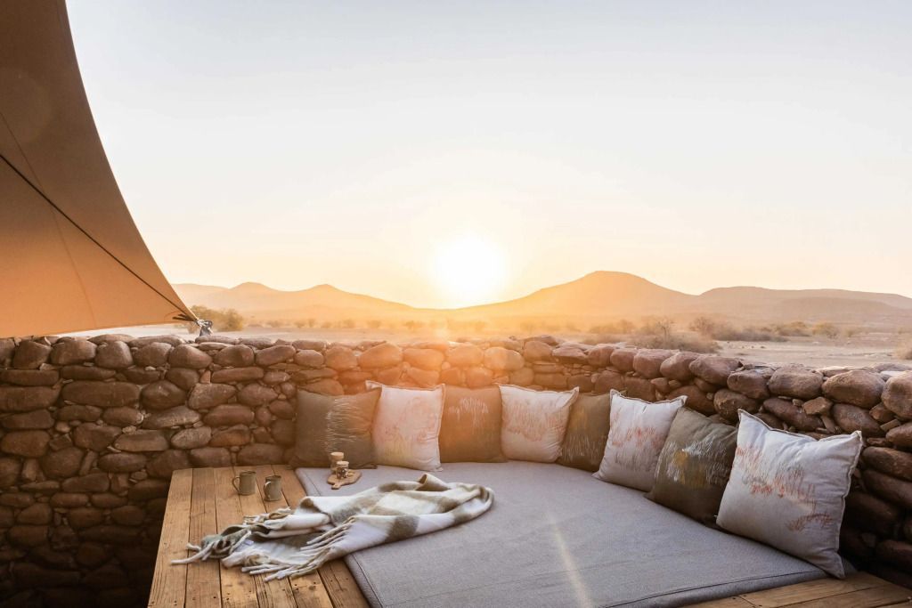 Entspannende Outdoor-Lounge mit Sitzkissen und Blick auf die Wüste bei Sonnenuntergang