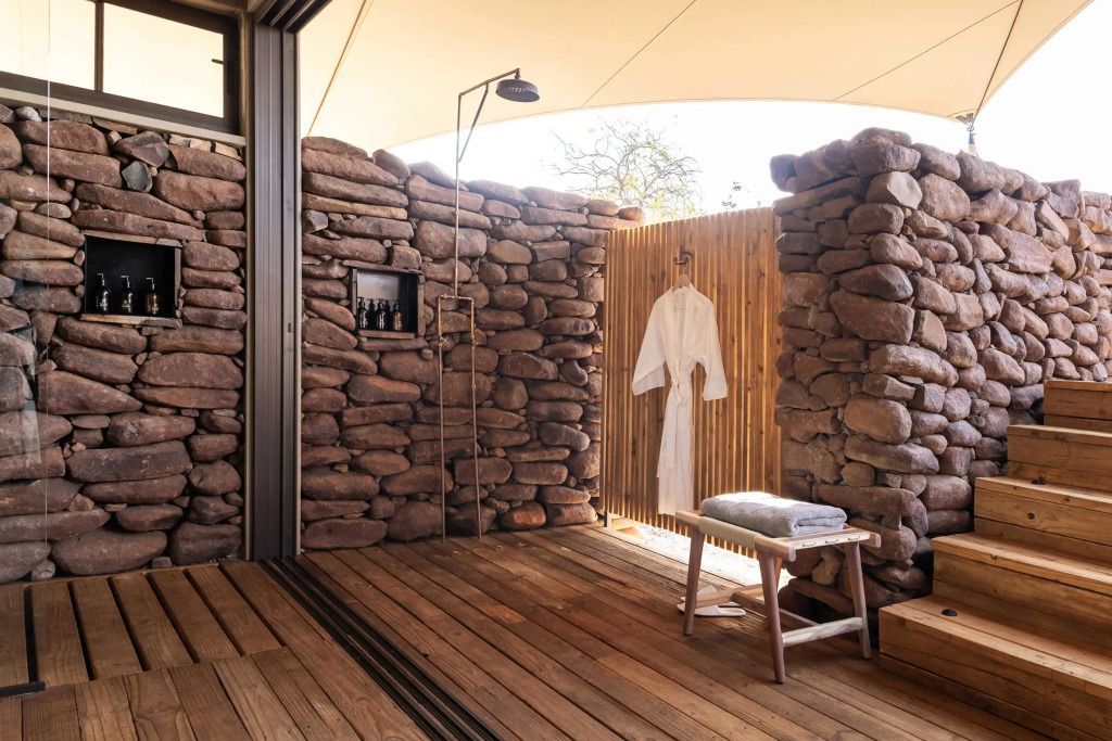 Offenes Badezimmer mit Natursteinelementen im Wilderness Desert Rhino Camp