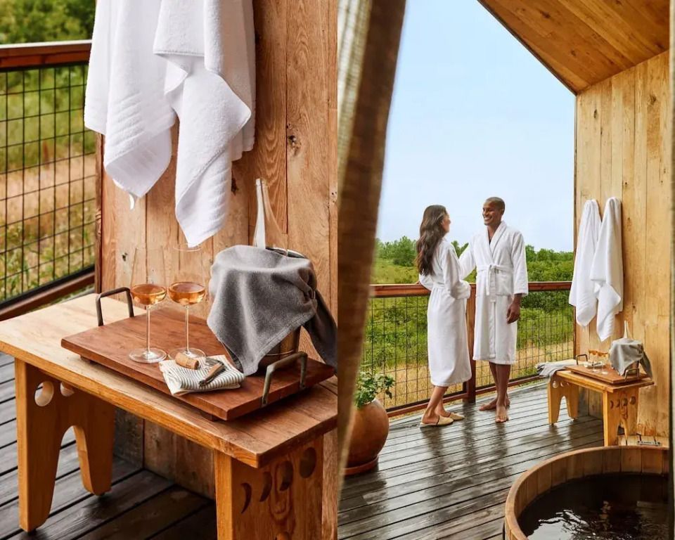 Suite mit Holzverkleidung und zwei Personen in Bademänteln auf Balkon mit Aussicht