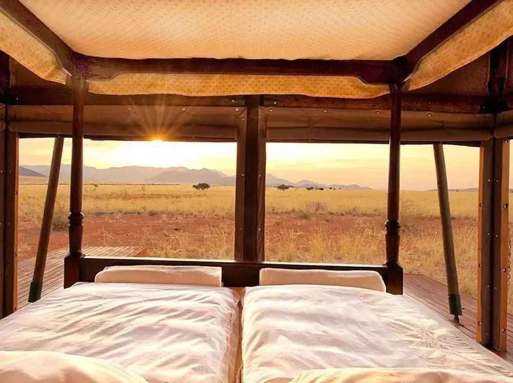 Bett mit Panoramablick auf die Wüstenlandschaft im Sonnenuntergang