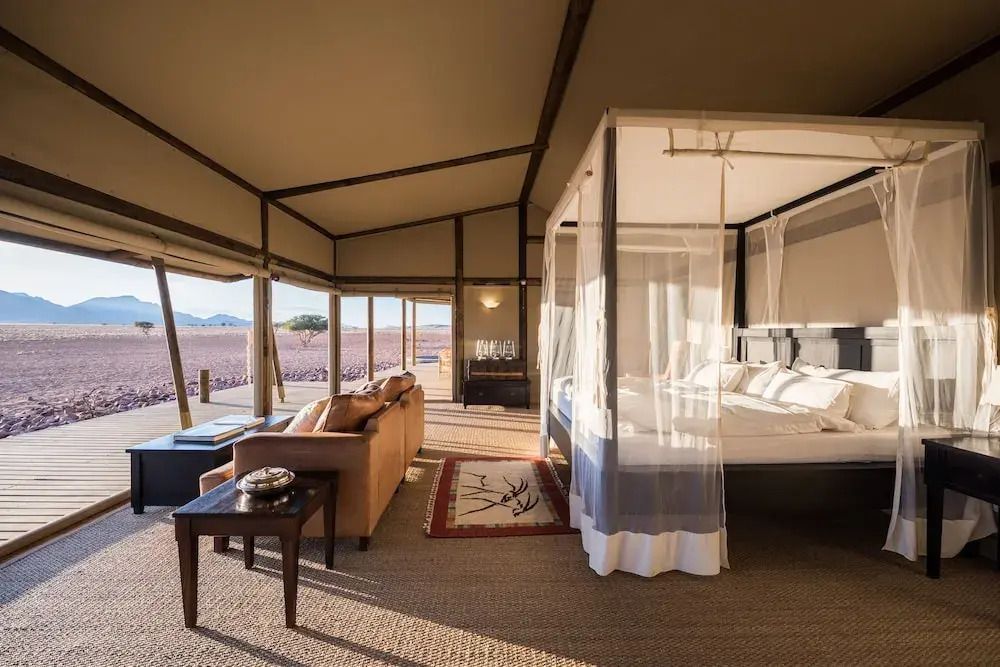 Offenes, stilvolles Zimmer mit Bett und Blick auf die weite Wüstenlandschaft
