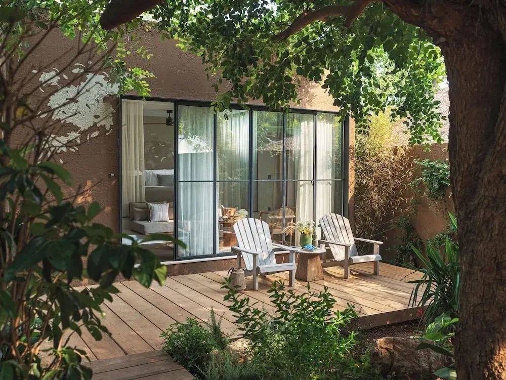 Holzterrasse der Junior-Suite mit Gartenblick und zwei weißen Liegestühlen