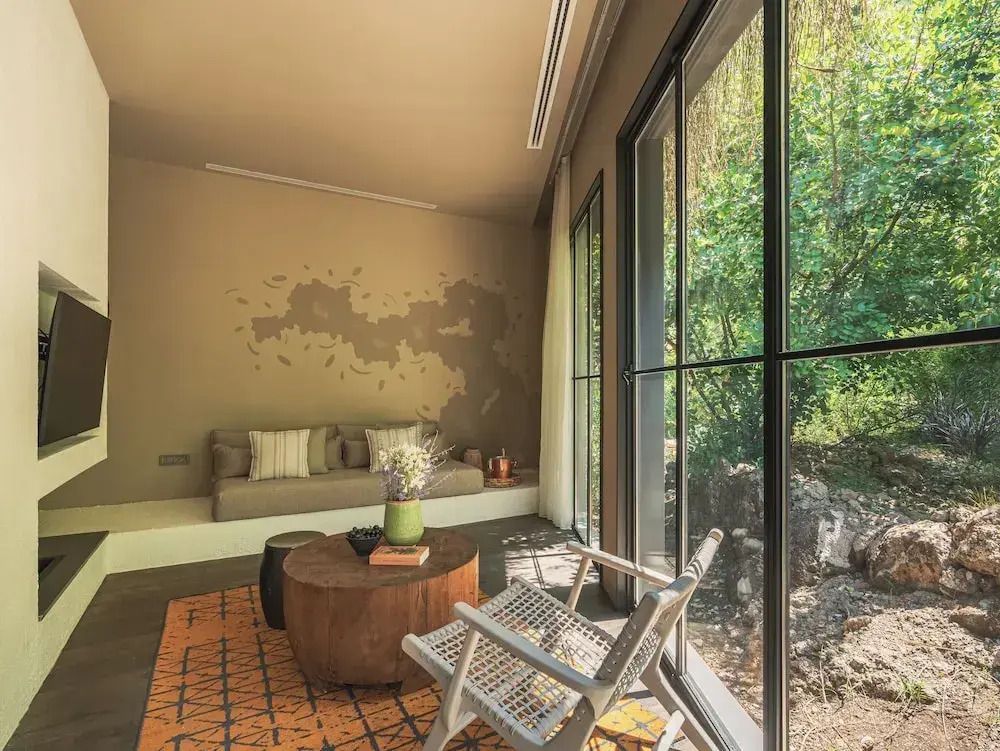 Suite mit Gartenblick, moderne Sitzecke und große Fenster mit Aussicht auf grünen Garten