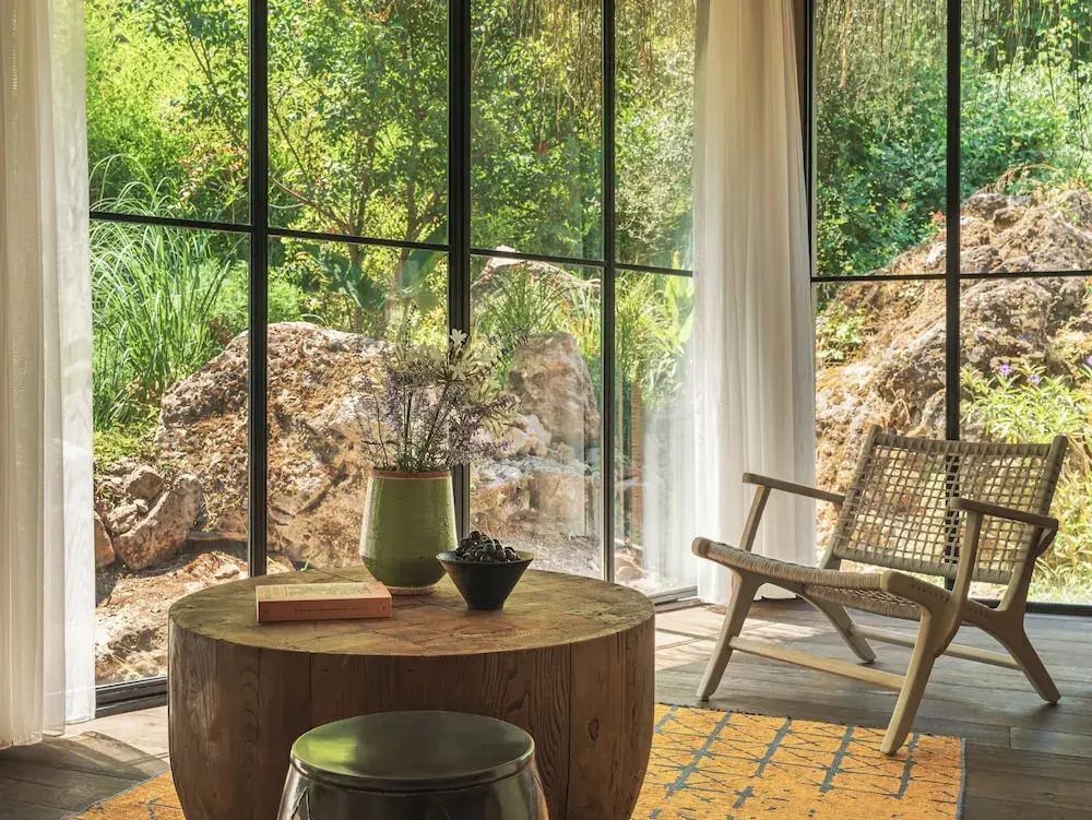 Gemütliche Sitzecke mit Tisch, Stuhl und Blick auf den Garten durch Panoramafenster