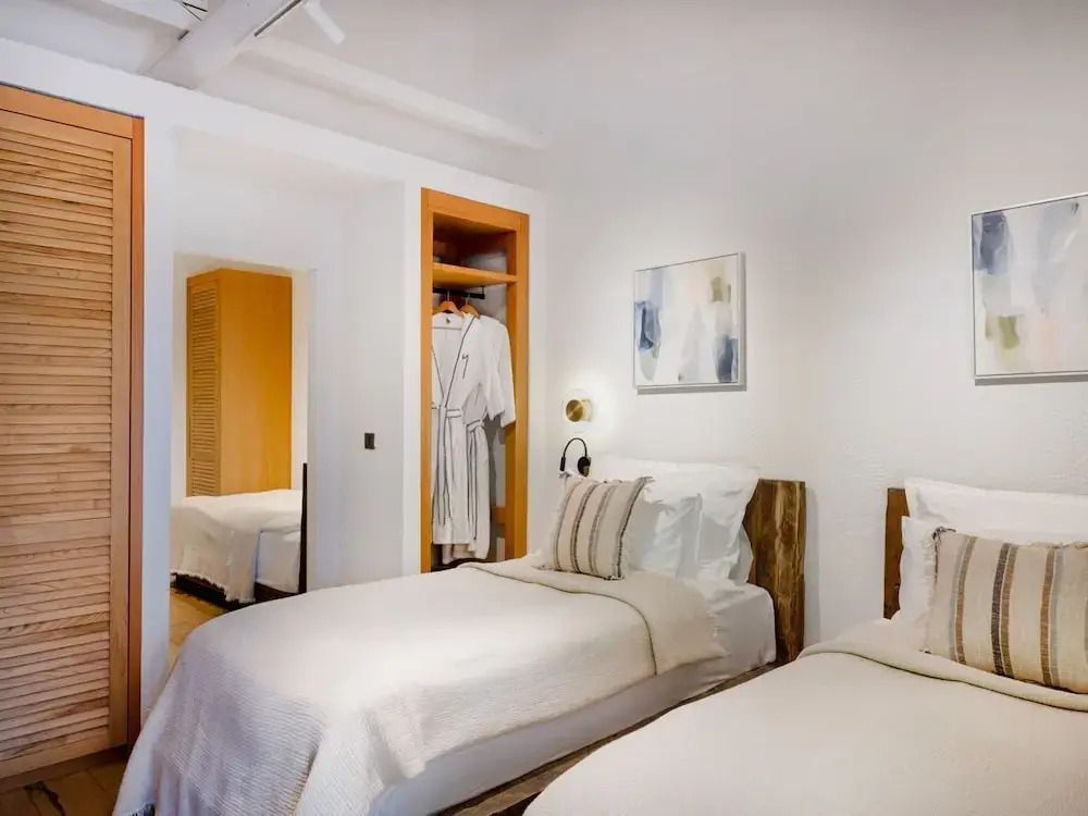 Zweibettzimmer in neutralen Tönen mit einem offenen Kleiderschrank