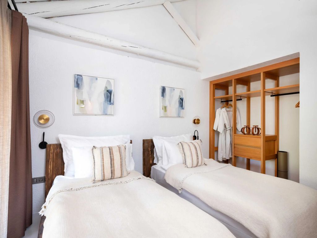 Zweibettzimmer in einer Villa mit heller Einrichtung und Holzdetails.