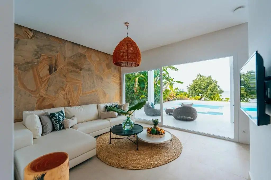 Geräumiges Wohnzimmer mit großen Fenstern zum Pool und stilvollen Möbeln