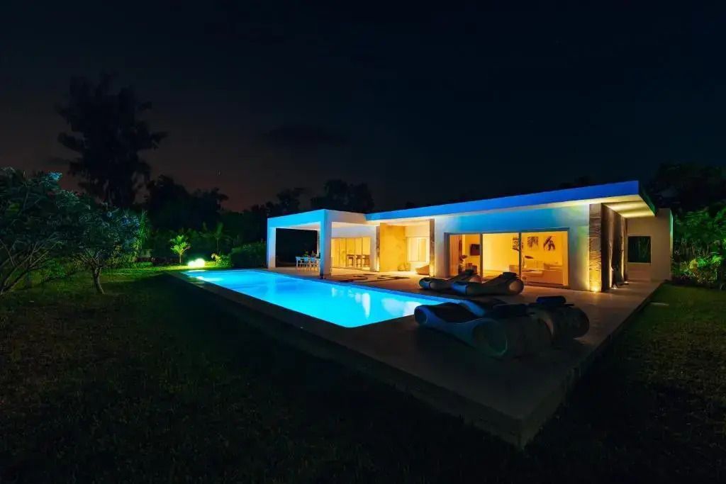 Villa mit beleuchtetem Pool und beleuchteten Räumen in der Dämmerung