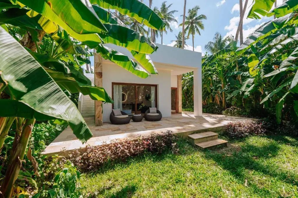 Moderne Villa mit Sitzbereich und tropischen Pflanzen umgeben