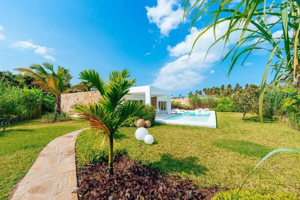 Grüne Gartenlandschaft mit Blick auf moderne Villa und Pool im Ycona Luxury Resort