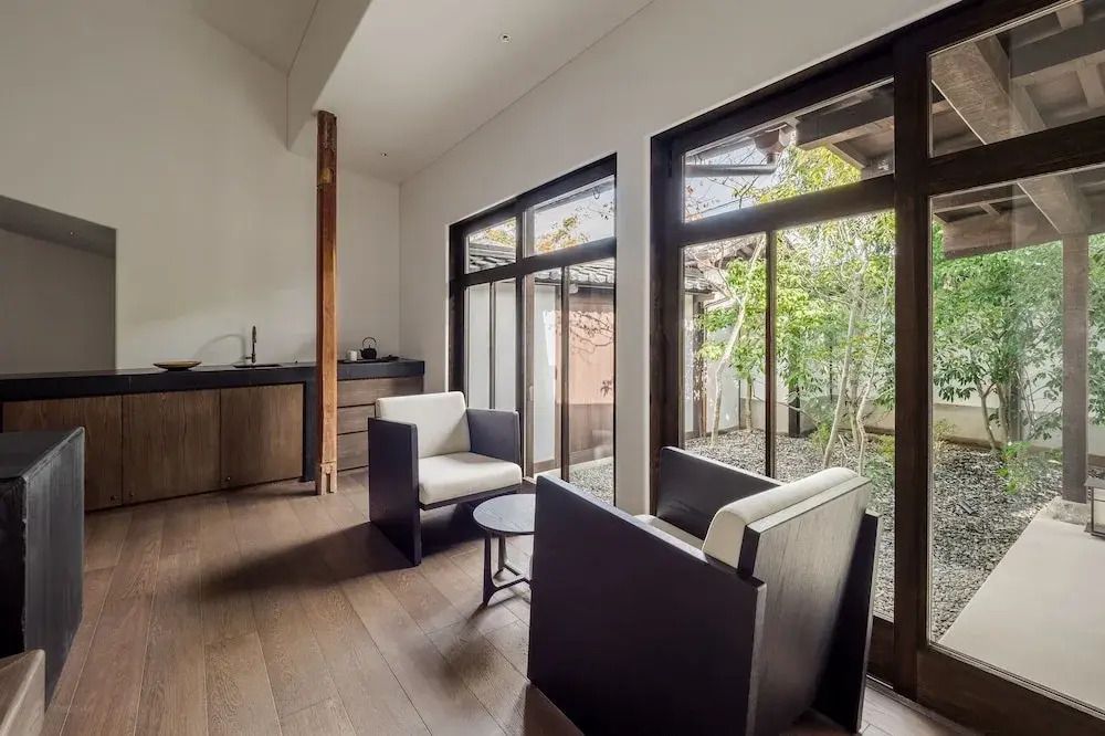 Lounge-Bereich mit Sesseln und großem Fenster zum Garten