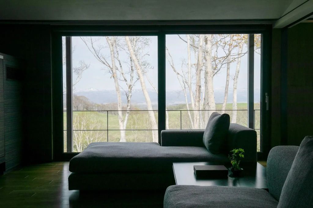 Geräumiges Deluxe-Zimmer mit Blick auf eine Waldlandschaft durch große Fenster