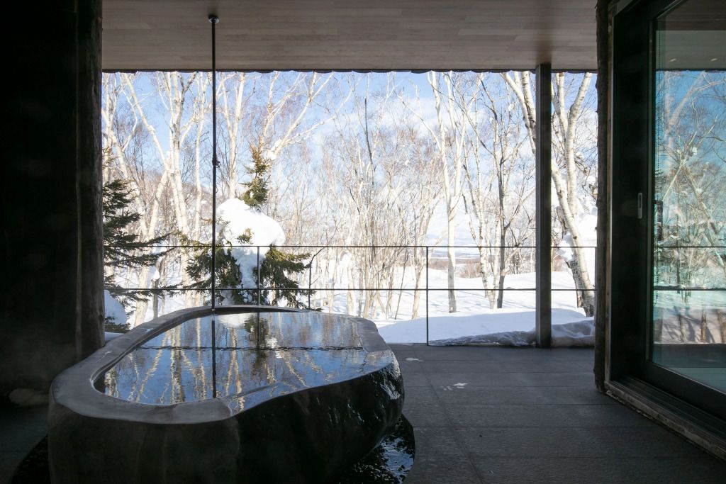 Offener Bereich mit modernem, freistehendem Pool und schneebedecktem Ausblick durch Fenster.