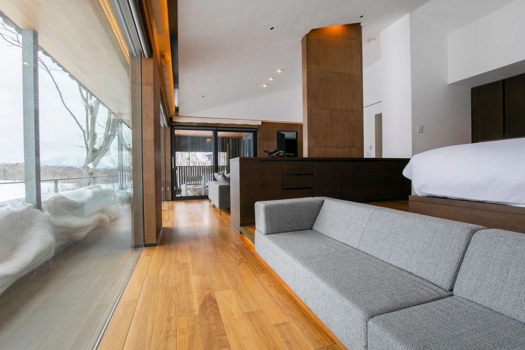 Langer Raum mit minimalistischem Sofa und großen Fenstern. Elegantes Holzmobiliar.
