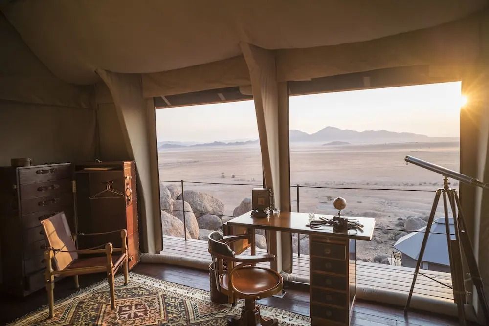 Gemütliche Sitzecke im Zelt mit Panoramablick auf Wüste und Berge