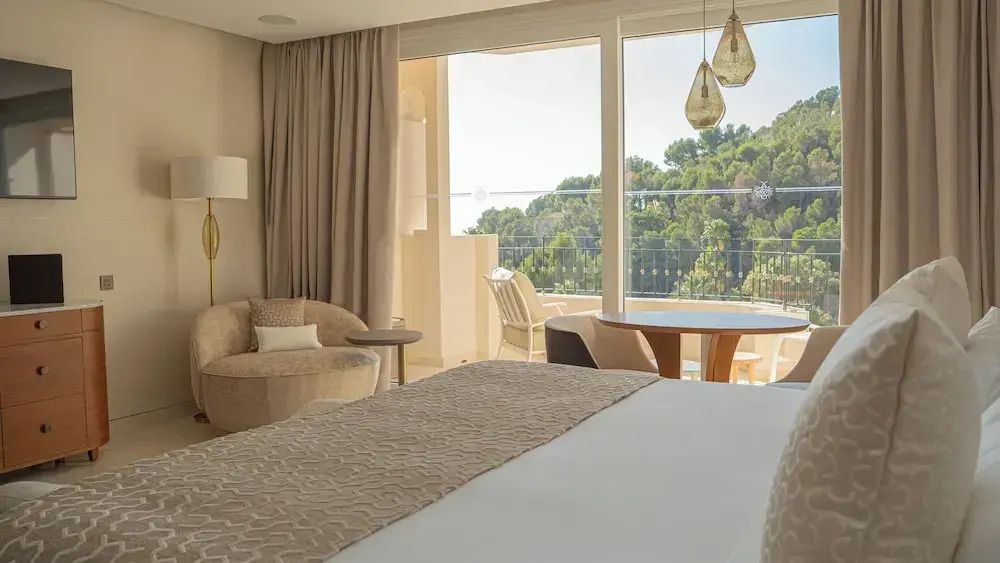 Deluxe Zimmer mit Bett, Sitzbereich und großem Fenster mit Balkonblick
