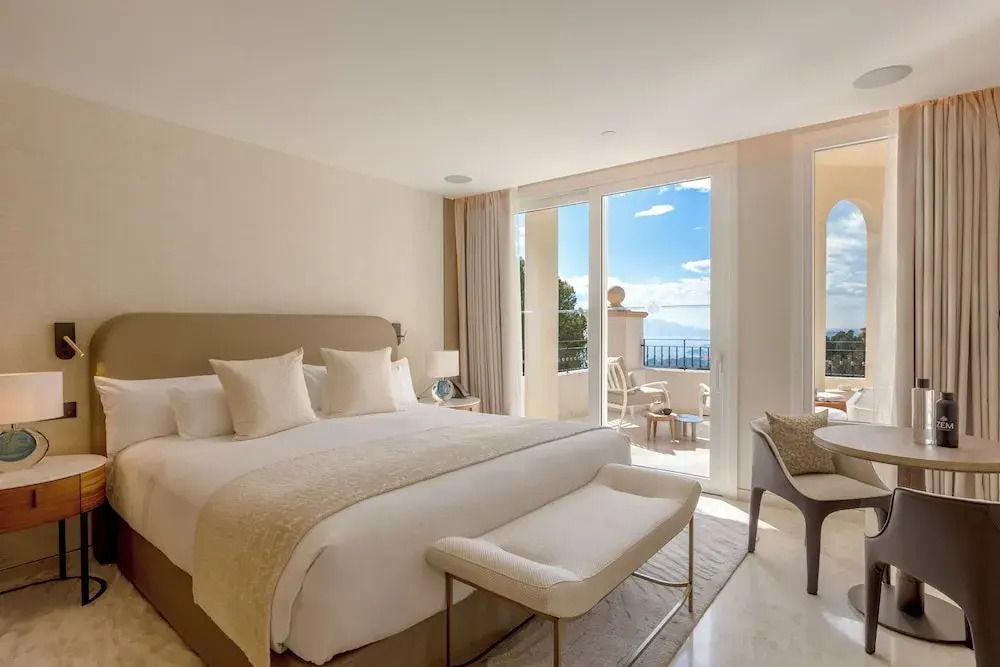 Helles Schlafzimmer mit Doppelbett und Balkon mit Meerblick