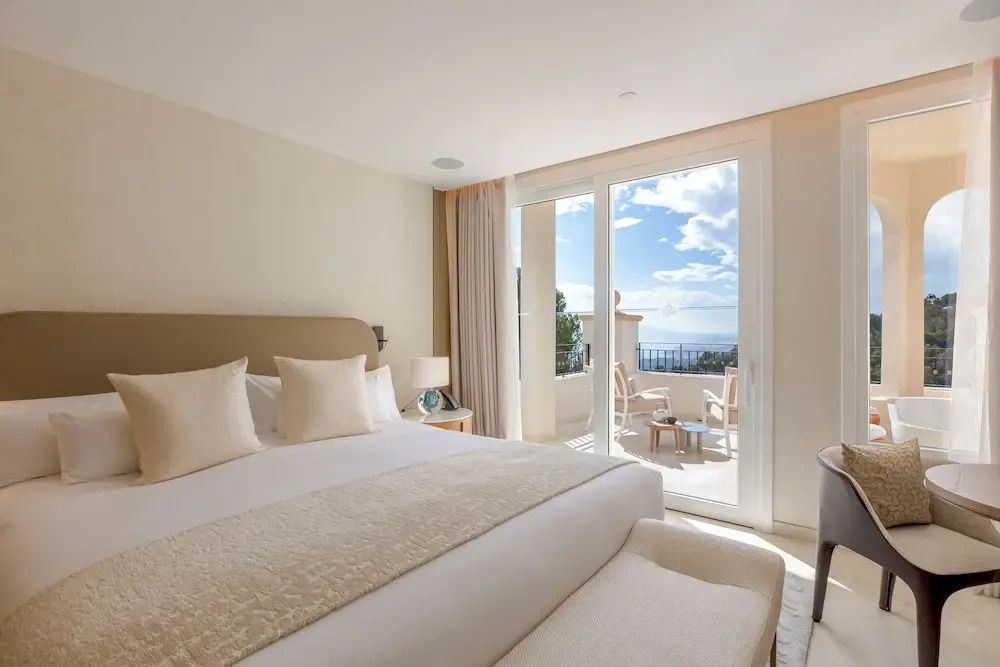 Helles Schlafzimmer mit Doppelbett und Balkon mit Meerblick
