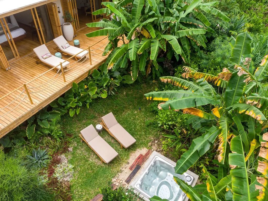 Garten mit üppiger Vegetation, Liegestühlen und privatem Whirlpool