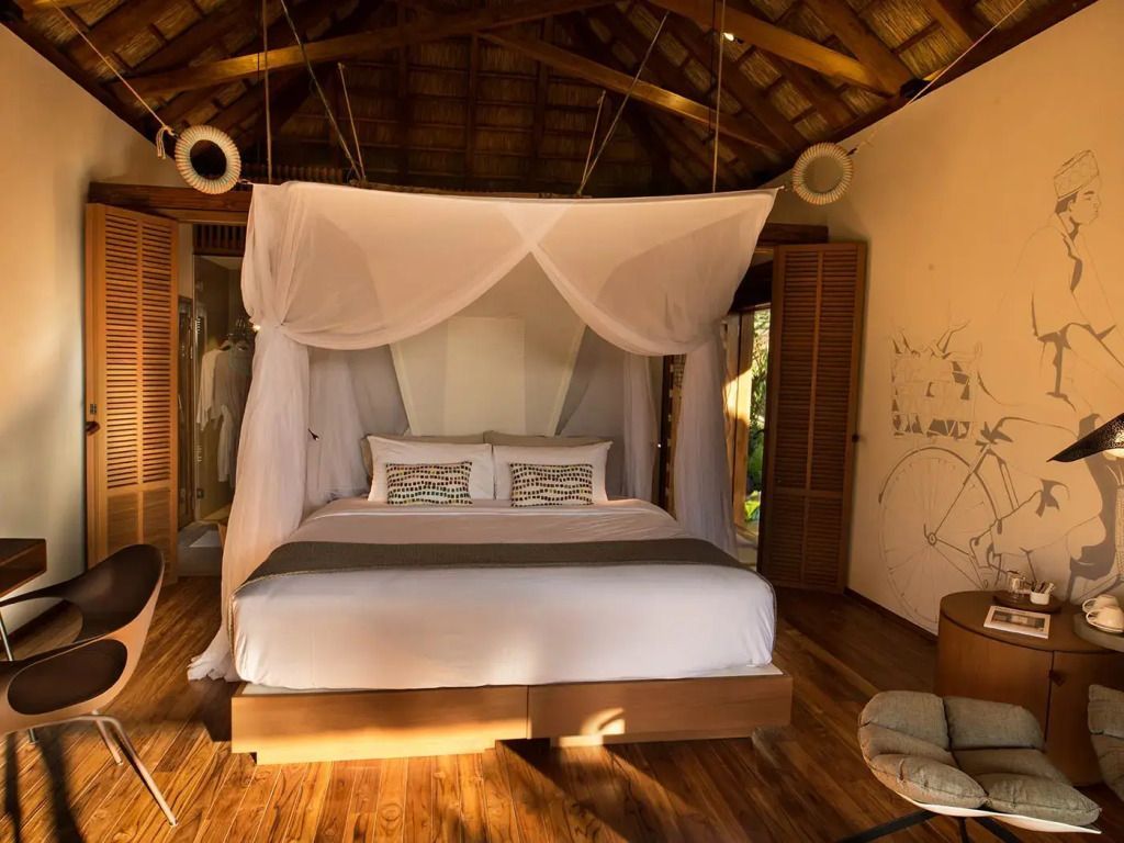 Schlafzimmer mit Himmelbett in einem Bungalow mit Holzdach.