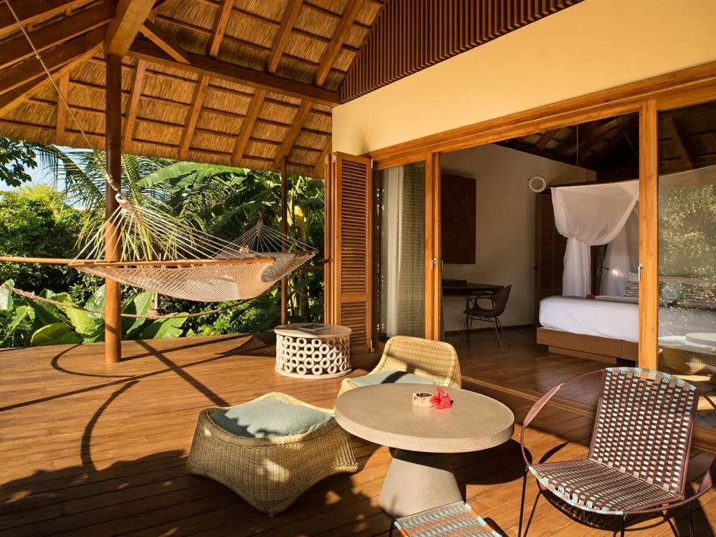 Terrasse mit Sitzgelegenheiten und Hängematte vor einem Bungalow.
