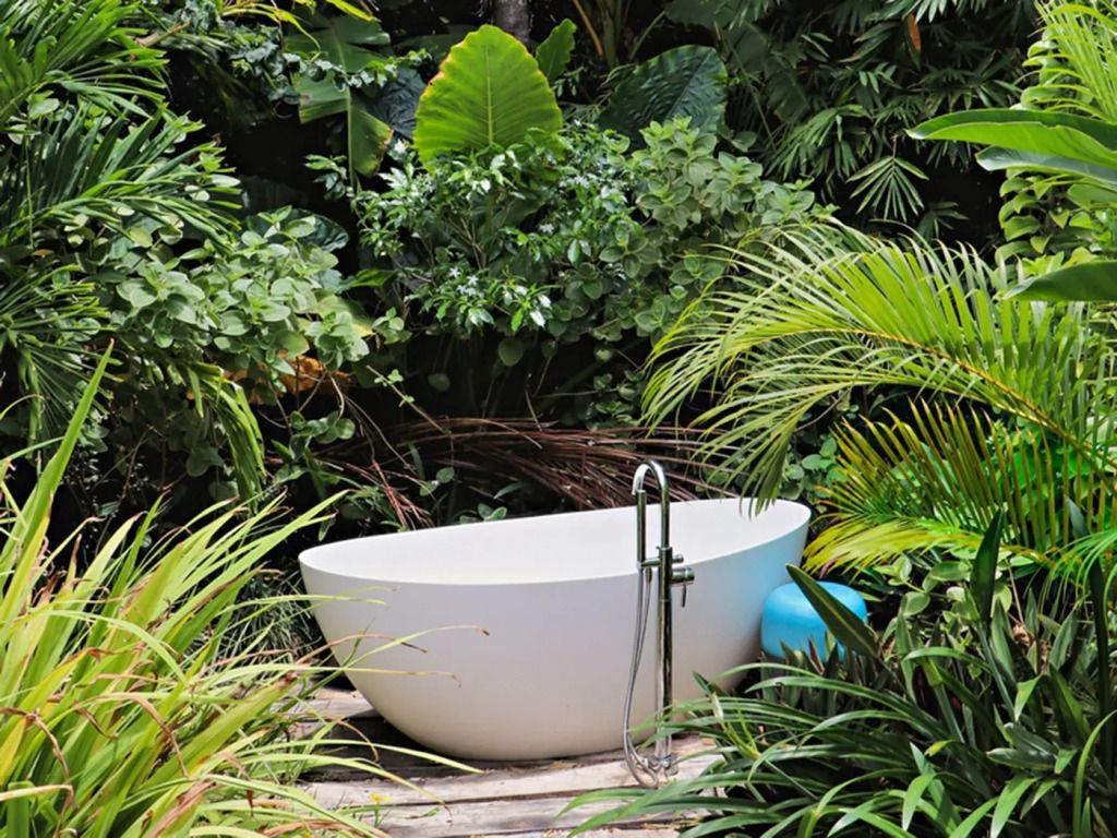 Freistehende Badewanne umgeben von üppiger tropischer Vegetation