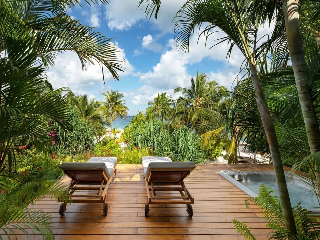 Sonnenliegen auf Holzterrasse mit Blick auf tropischen Garten in Zuri Zanzibar