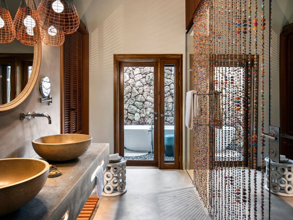 Luxuriöses Badezimmer mit Steinwaschbecken und Natursteinwand in Zuri Zanzibar